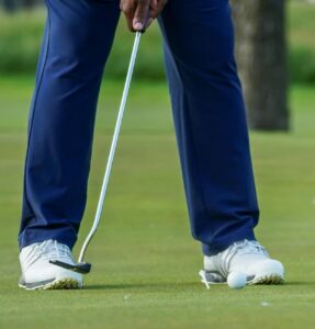 person positioning a golf club